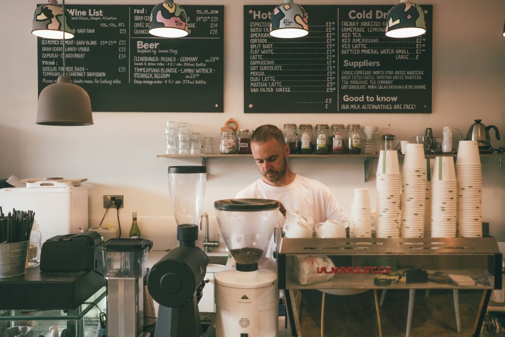 a local business owner operating a coffee shop pouring drip coffee
